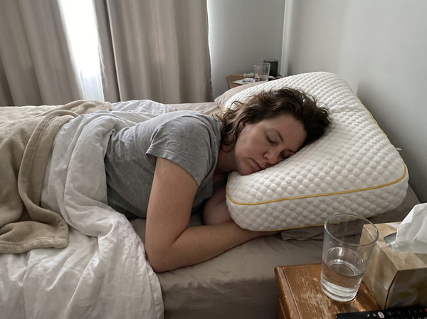 Customer asleep on her side on a Pillowash washable pillow in a lived-in bedroom at dawn