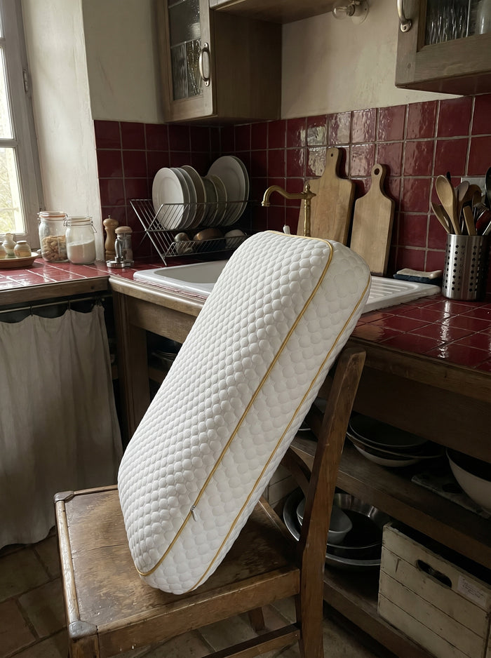 Freshly washed Pillowash pillow standing upright on a wooden chair to air dry in a rustic tiled kitchen