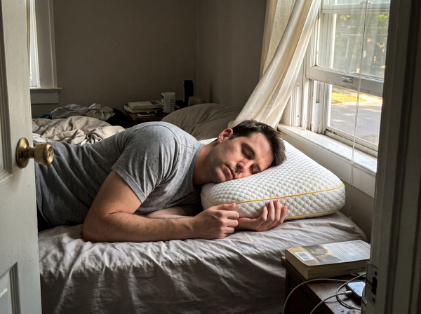 Man in his thirties side-sleeping on a Pillowash washable pillow beside an open bedroom window